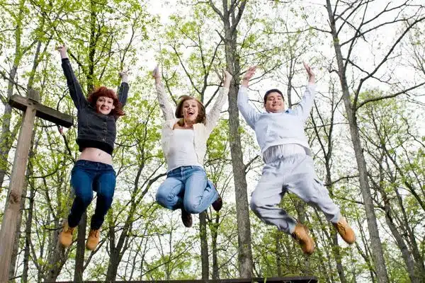 three people jumping in the air gleefully against forest trees